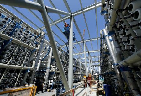 A worker on a scissor lift works between rows of reverse osmosis filters as construction continues on the Western Hemisphere's largest seawater desalination plant in Carlsbad, California, April 14, 2015. REUTERS/Mike Blake