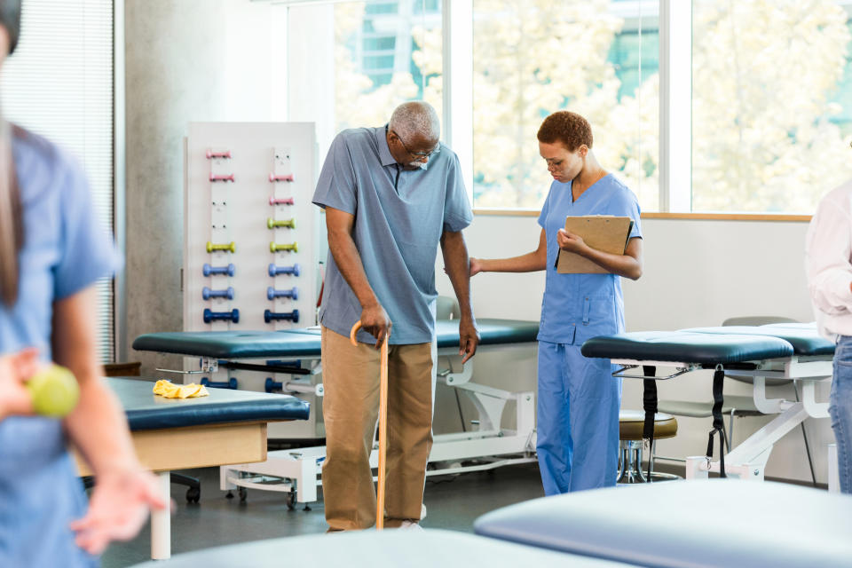 A nurse helps an elderly person walk