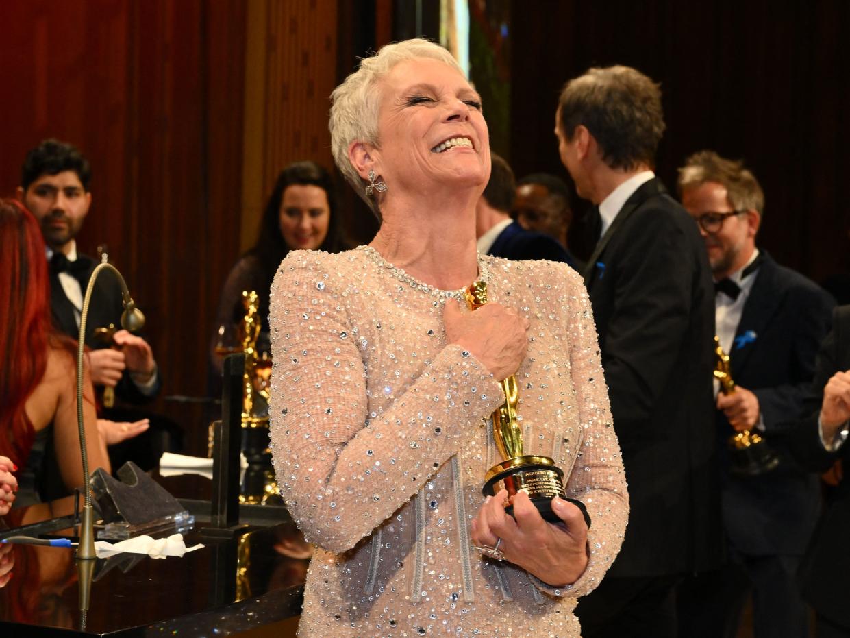 Jamie Lee Curtis clutches her Oscar backstage, smiling with her eyes shut.