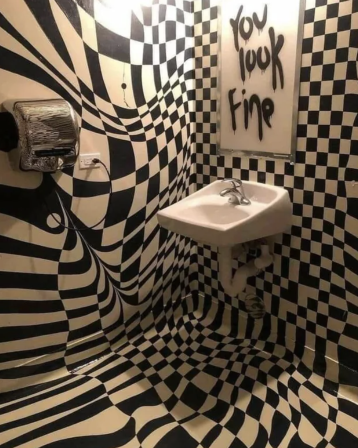 Optical illusion bathroom with checkered pattern and mirror message saying "you look fine"