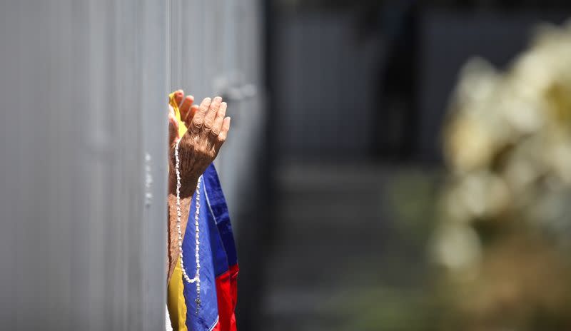 A woman holds a Venezuelan flag and rosary outside of the Our Lady of La Candelaria church in Caracas