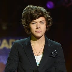 Close-up of Harry holding a microphone and with lots of hair, including a side bang