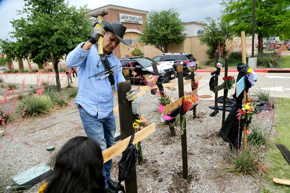 Roberto Marquez is pictured constructing a wooden cross memorial at the scene of a mass shooting a day earlier at Allen Premium Outlets in Allen, Texas.