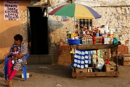 A woman holding a child sits in front of her stall in Sambizanga informal settlement, outside the capital Luanda in this August 28, 2012 file photo. REUTERS/Siphiwe Sibeko/Files