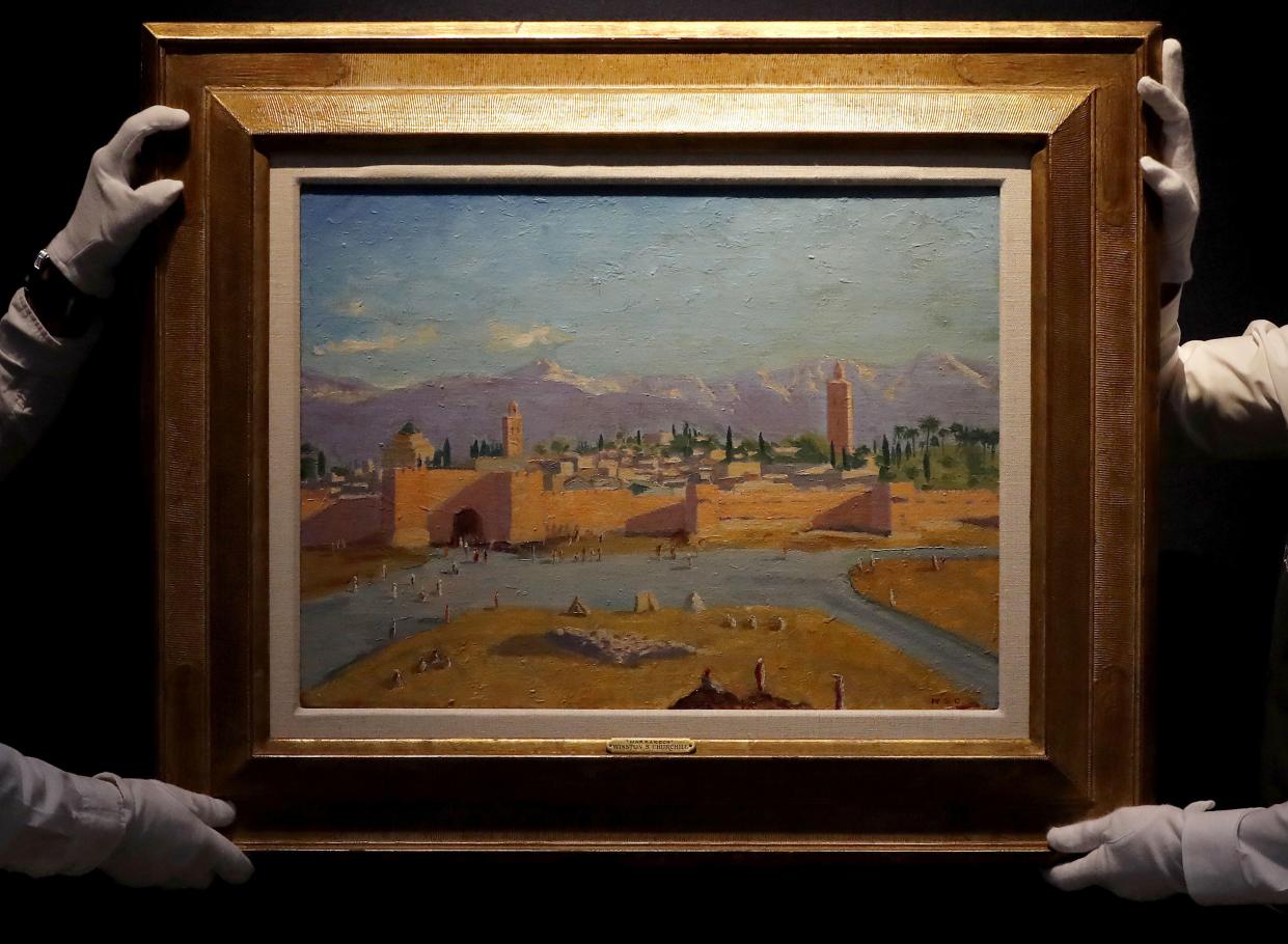FILE - In this Wednesday, Feb. 17 photo, Christie's employees adjust an oil on canvas painting by Sir Winston Churchill painted in Jan. 1943 called 'Tower of the Koutoubia Mosque' during an Art pre-sale photo call at Christie's auction house in London. 