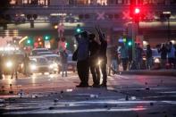 People stand amid debris on a road after tear gas is used to disperse protesters as demonstrations continue in Minneapolis