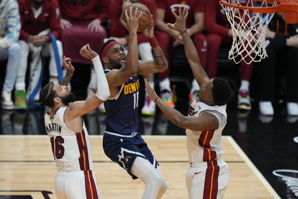 Denver Nuggets forward Bruce Brown (11) drives to the basket as Miami Heat forward Caleb Martin (16) and guard Kyle Lowry (7) defend during the second half of Game 4 of the basketball NBA Finals, Friday, June 9, 2023, in Miami. (AP Photo/Lynne Sladky)