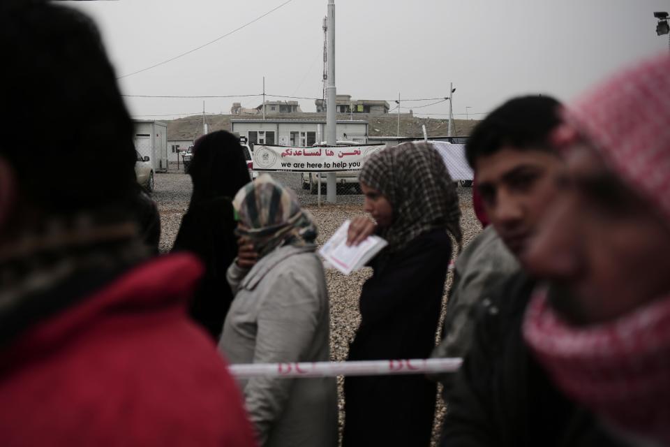 Displaced people wait for aid at a camp east of Mosul, Iraq, Wednesday, Feb. 15, 2017. The United Nations says they are temporarily pausing aid operations to neighborhoods in eastern Mosul retaken from the Islamic State group for security reasons as IS insurgent and counter attacks continue to inflict heavy civilian casualties there.(AP Photo/Bram Janssen)