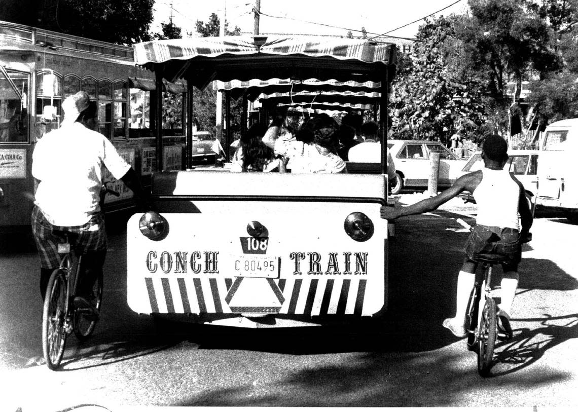 Locals ride alongside the Conch Train in 1981. Tour guide drivers roll up and down city streets and point out landmarks to the tourists on board. Miami Herald File