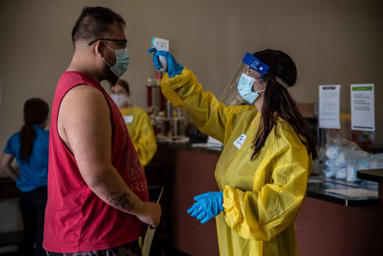 A worker takes the temperature of a patient at a vaccination site at a senior center on March 29, 2021, in San Antonio, Texas.