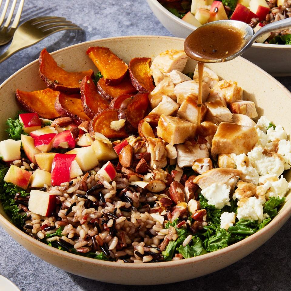 copycat sweetgreen harvest bowl with dressing drizzling over it from a spoon