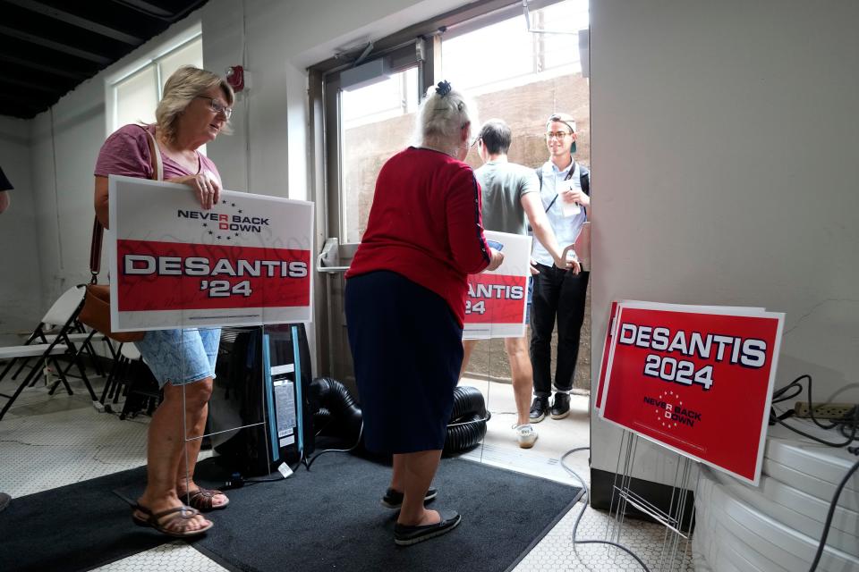 Local residents carry campaign signs after listening to Republican presidential candidate Florida Gov. Ron DeSantis speak at a meet and greet at the Hotel Charitone, Thursday, July 27, 2023, in Chariton, Iowa.