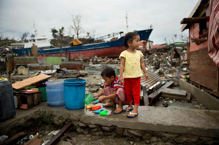 A young boy cleans salvaged toys near a ship washed ashore by Super Typhoon Haiyan in Tacloban on November 23, 2013