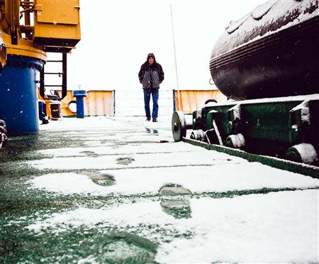A crew member of the Akademik Shokalskiy walks on the snow-covered aft deck of the stranded ship in the Antarctic, December 29, 2013. REUTERS/Andrew Peacock