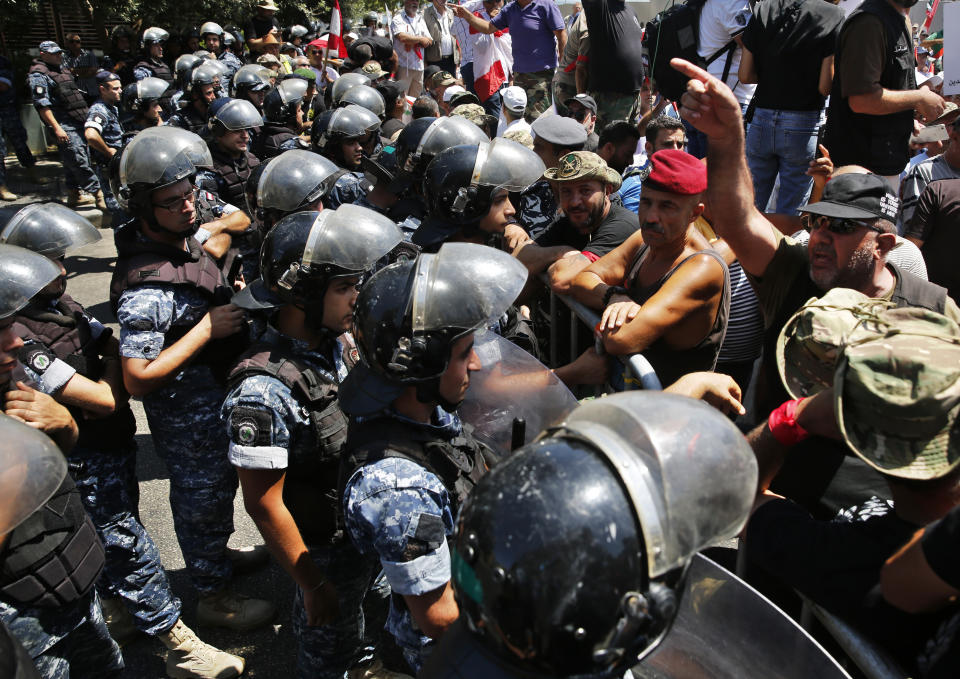 Retired Lebanese soldiers, right, protest in front of riot police who blocked a road leading to the parliament building where lawmakers and ministers are discussing the draft 2019 state budget, in Beirut, Lebanon, Tuesday, July 16, 2019. The lawmakers have begun discussing the budget amid tight security and limited protests against proposed austerity measures. The proposed budget aims to avert a financial crisis by raising taxes and cutting public spending in an effort to reduce a ballooning deficit. (AP Photo/Hussein Malla)