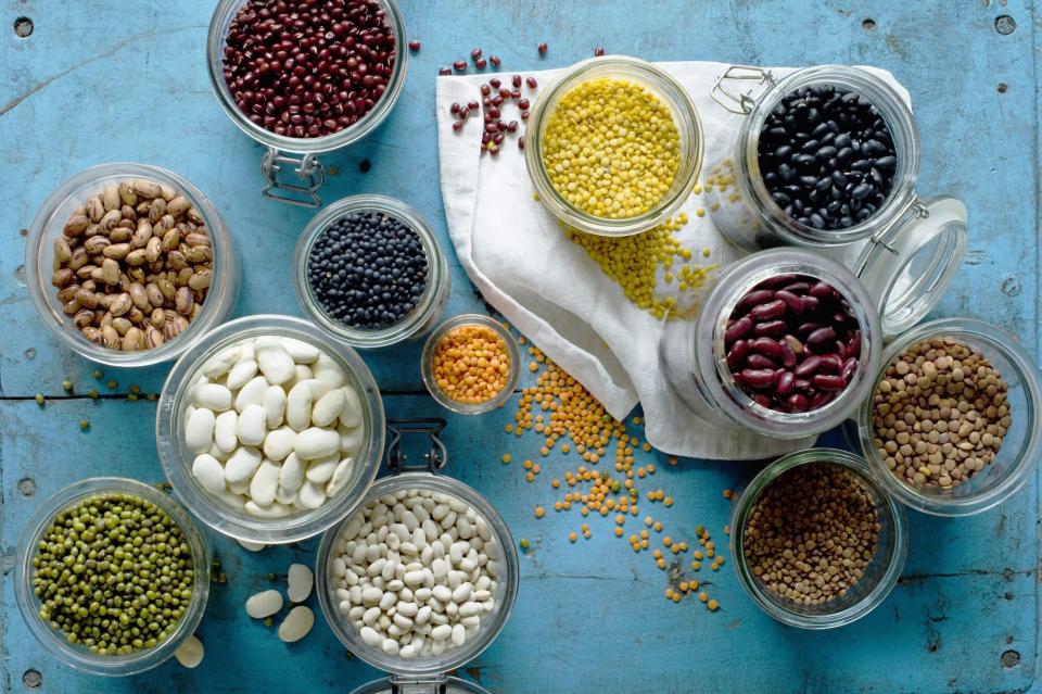 Various beans and lentils in jars on bluerustic wooden surface