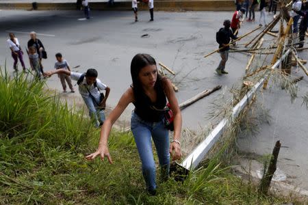 People walk around of a blockade built by opposition supporters during a rally against Venezuela's President Nicolas Maduro's government in Caracas, Venezuela, July 28, 2017. REUTERS/Andres Martinez Casares