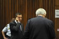 Olympic and Paralympic track star Oscar Pistorius talks on a mobile phone as he makes his way to the dock in the North Gauteng High Court in Pretoria March 24, 2014. The track star, nicknamed the "Blade Runner", is on trial for the murder of his girlfriend Reeva Steenkamp at his suburban Pretoria home on Valentine's Day last year. He has pleaded not guilty, saying he mistook Steenkamp for an intruder. REUTERS/Ihsaan Haffejee/Pool (SOUTH AFRICA - Tags: SPORT CRIME LAW ATHLETICS)