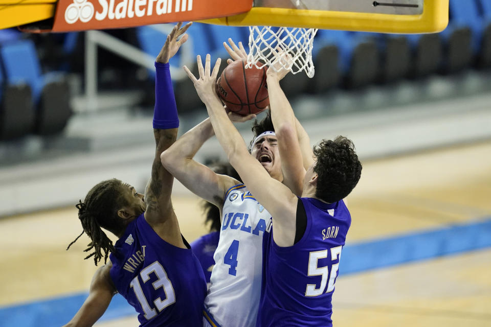 Washington forward Hameir Wright (13) and center Riley Sorn (52) break up a shot by UCLA guard Jaime Jaquez Jr. (4) during the second half of an NCAA college basketball game Saturday, Jan. 16, 2021, in Los Angeles. (AP Photo/Ashley Landis)