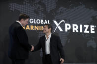 Tesla CEO Elon Musk, left, shakes hands with XPRIZE founder and Executive Chairman, Peter Diamandis, during the presentation of the XPRIZE for Children's Literacy Wednesday, May 15, 2019, in Los Angeles. A California company founded by game-developer parents who wanted to help their special-needs son is sharing a $10 million XPRIZE award with a London-based educational nonprofit for programs created to teach illiterate children how to teach themselves to read. (AP Photo/Marcio Jose Sanchez)