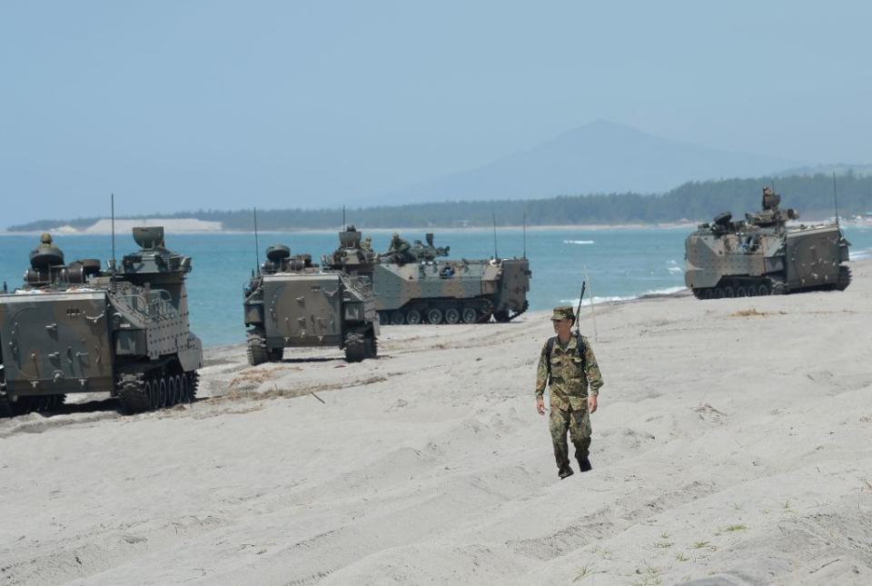 A Japanese soldier walks past amphibious assault vehicles. Source: Getty