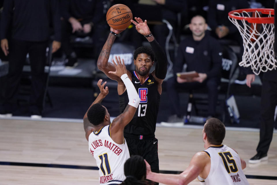 Los Angeles Clippers guard Paul George (13) shoots over Denver Nuggets guard Monte Morris (11) during the second half of an NBA conference semifinal playoff basketball game Tuesday, Sept. 15, 2020, in Lake Buena Vista, Fla. (AP Photo/Mark J. Terrill)