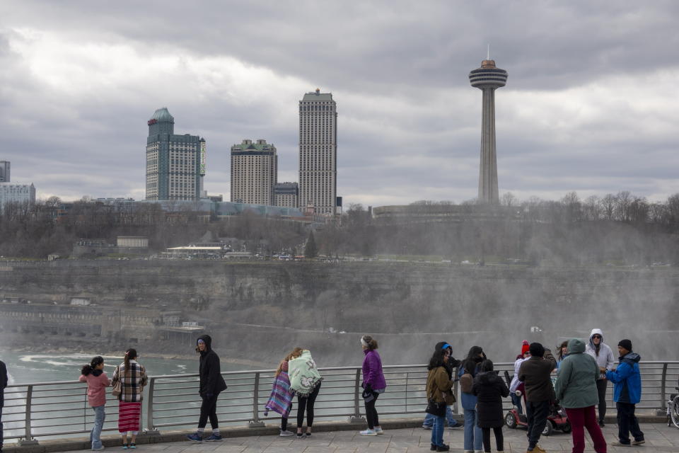 Tourists on the American side of Niagara Falls take photos in Niagara Falls, N.Y. on Friday, March 29, 2024. Ontario's Niagara Region has declared a state of emergency as it readies to welcome up to a million visitors for the solar eclipse on April 8. (Carlos Osorio/The Canadian Press via AP)