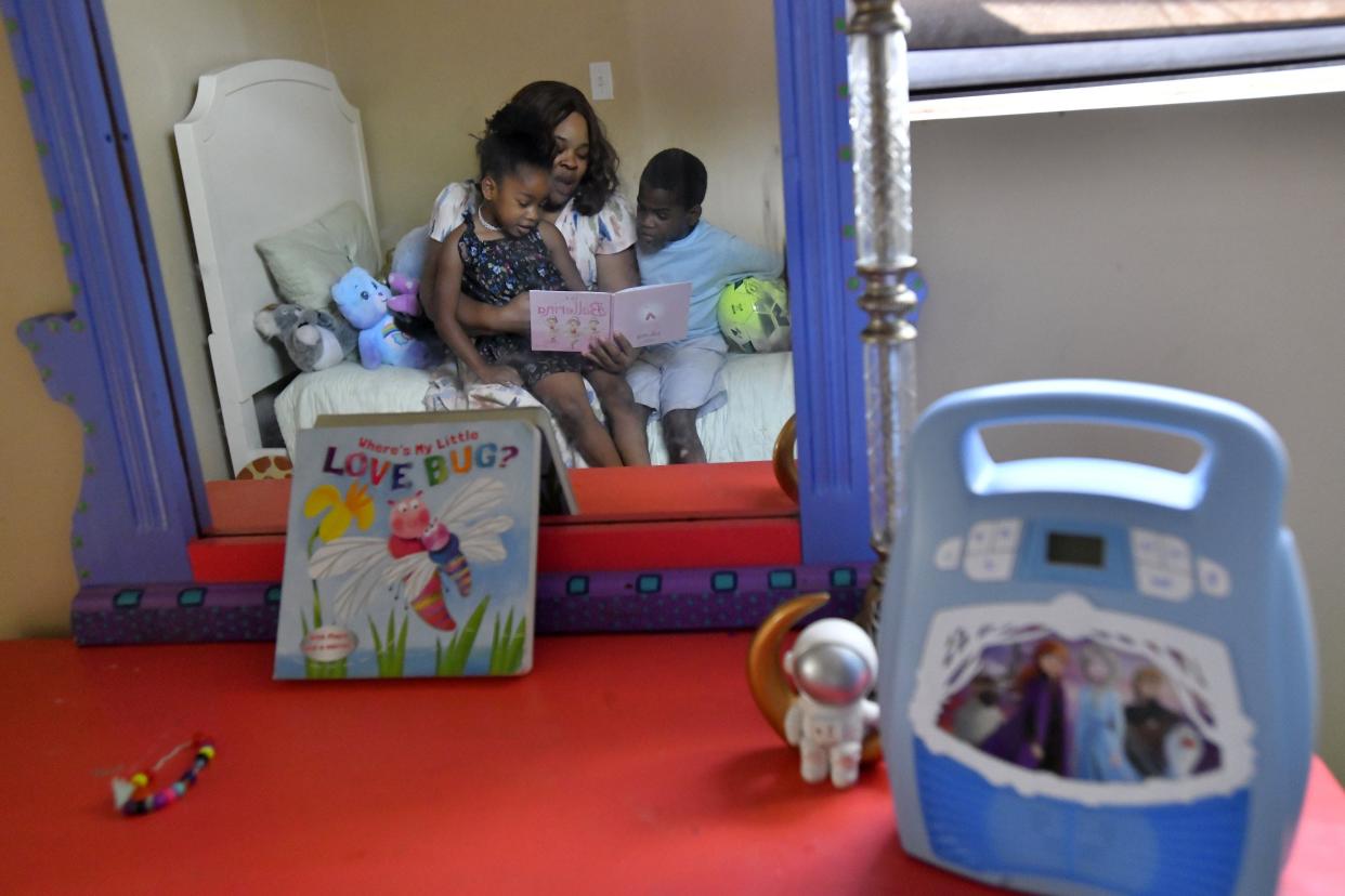Reflected in a mirror, Jasmine Jackson reads to two of her children, 5-year-old daughter Kamari Phillips, left, and 8-year-old son Keyon Phillips in the bedroom the siblings share in their new rental home on Jacksonville's Northside. Jackson and her three children were homeless for three months last year.