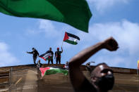 Demonstrators holding flags stand on the top of a building during a protest outside Israeli Consulate against Israel and in support of Palestinians, Saturday, May 15, 2021 in the Westwood section of Los Angeles. (AP Photo/Ringo H.W. Chiu)