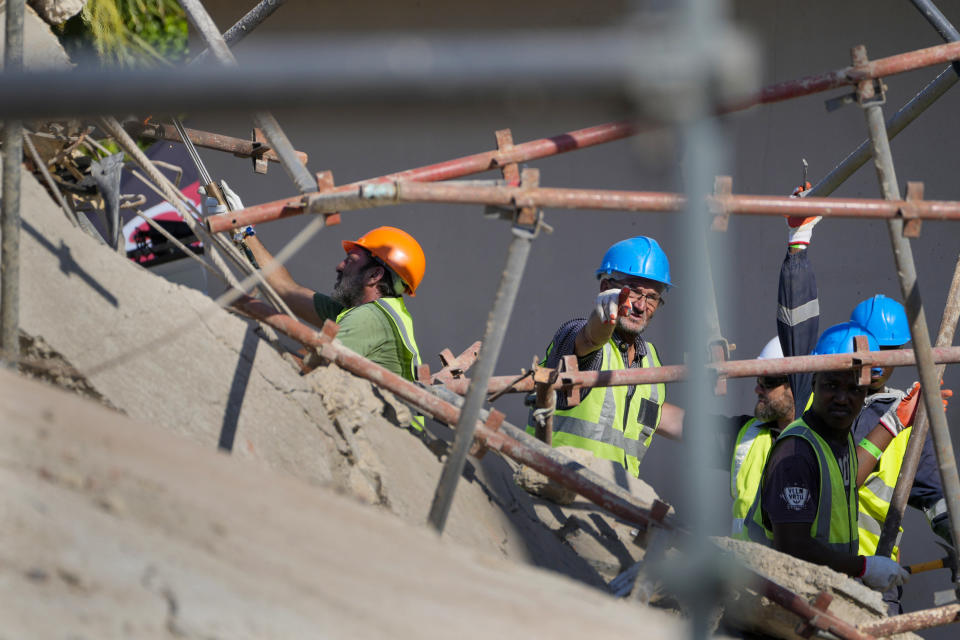 Rescue workers search the site of a building collapse in George, South Africa, Wednesday, May 8, 2024. Rescue teams searching for dozens of construction workers missing after a multi-story apartment complex collapsed in the coastal city have brought out more survivors as the operation entered a second night of desperate work to find anyone alive in the mangled wreckage.(AP Photo/Jerome Delay)