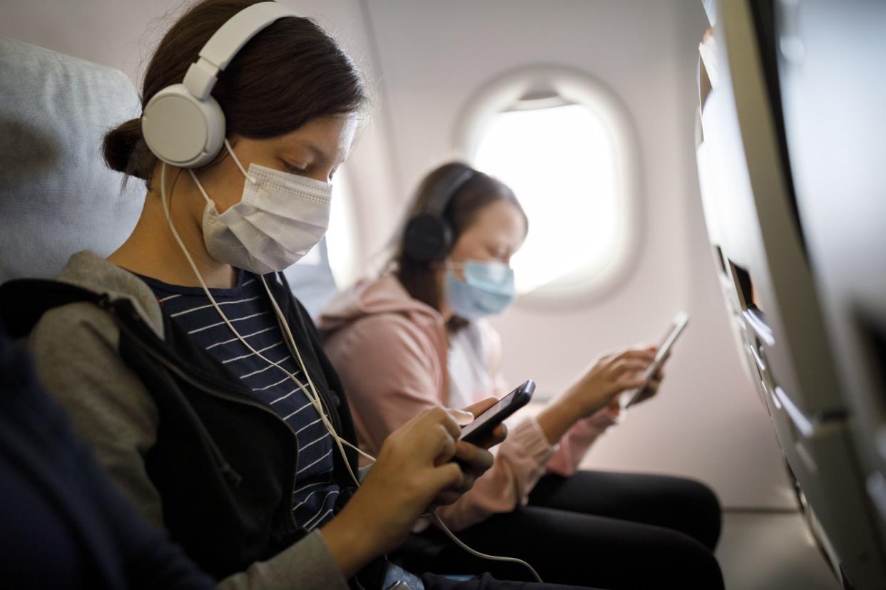 Kids with face protective mask using mobile phone in airplane