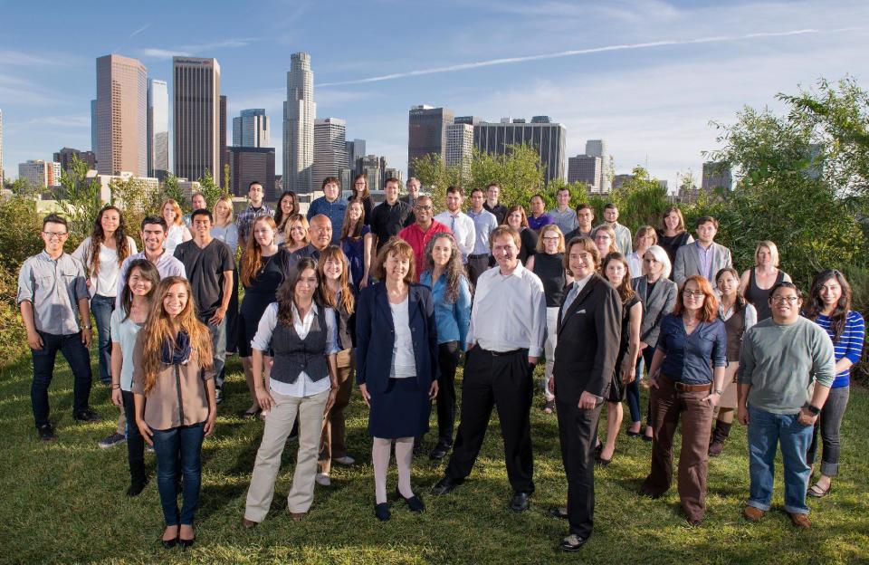 In this April 8, 2014 photo provided by the Los Angeles Register, some of the newspaper's staff pose for a photo with the Los Angeles skyline in the background. Editor Ron Sylvester is at center right in the dark suit. Former greeting card executive Aaron Kushner is trying to turn the Orange County Register into a media giant in southern California, largely driven by paper and ink. The unconventional effort gets a jolt Wednesday, April 16, 2014, when Freedom Communications Inc., the company Kushner bought with other investors two years ago, launches the Los Angeles Register. (AP Photo/Los Angeles Register, Leonard Ortiz)