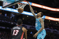 Charlotte Hornets forward P.J. Washington (25) dunks as Miami Heat center Bam Adebayo (13) looks on during the first half of an NBA basketball game in Charlotte, N.C., Sunday, Jan. 29, 2023. (AP Photo/Nell Redmond)