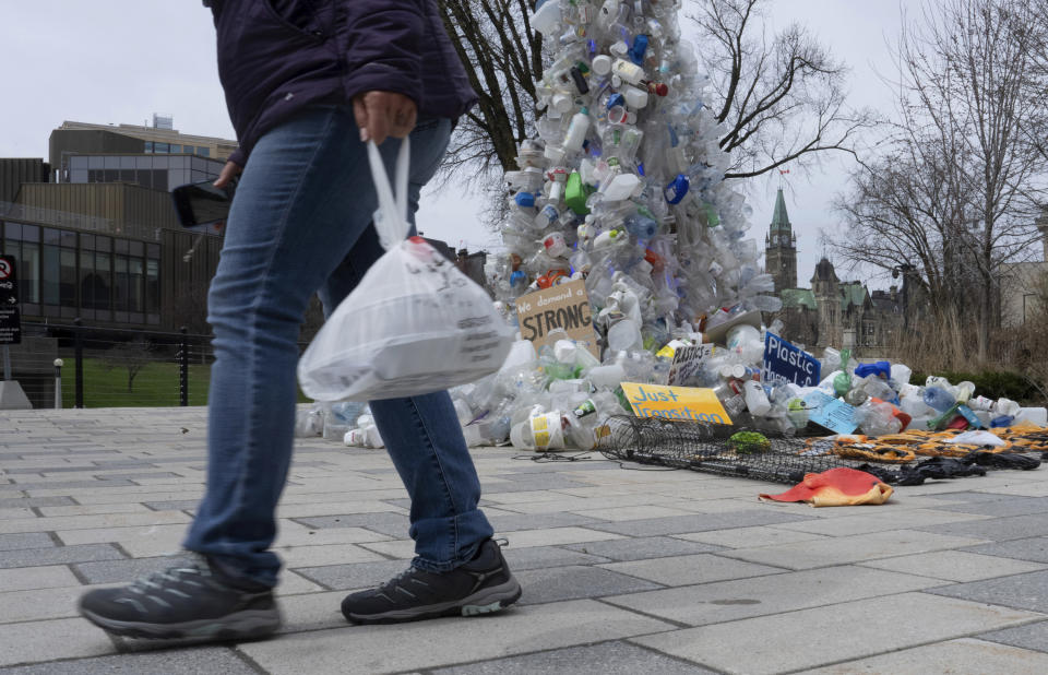 FILE - A person carries food in a plastic bag past an art installation outside the a United Nations conference on plastics on April 23, 2024, in Ottawa, Ontario. (Adrian Wyld/The Canadian Press via AP, File)