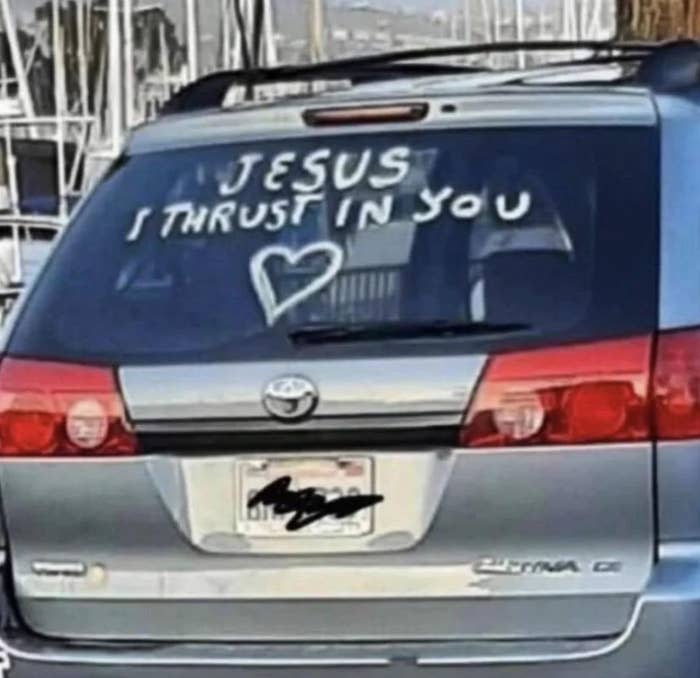 A silver Toyota Sienna has "Jesus I thrust in you" written on the back window along with a heart shape