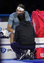 Greece's Stefanos Tsitsipas talks with medical assistant during the singles tennis match against Denmark's Holger Rune, of the ATP World Tour Finals at the Pala Alpitour, in Turin, Italy, Tuesday, Nov. 14, 2023. (AP Photo/Antonio Calanni)