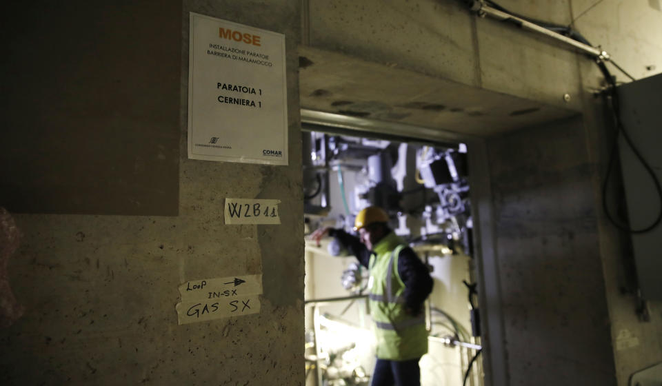 A worker walks in an undersea tunnel part of a plan to protect the city of Venice from flooding, in Venice, Italy, Friday, Nov. 29, 2019. The barrier system is made up of 78 giant flood gates, each 20 meters long which are attached by hinges to giant cement blocks placed on the seabed along the three openings from the sea into the lagoon, Malamocco, Chioggia and the Lido. (AP Photo/Antonio Calanni)