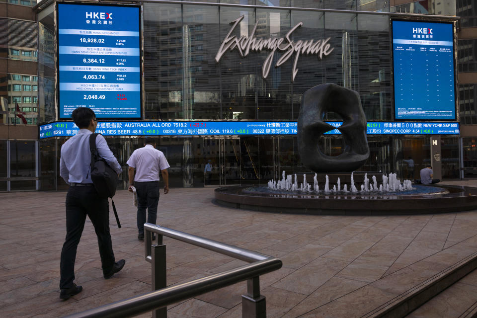 Pedestrians pass by the Hong Kong Stock Exchange electronic screen in Hong Kong, Friday, July 21, 2023. Shares were mixed Friday in Asia after the latest rally on Wall Street fizzled, with big declines for Tesla, Netflix and other big tech-oriented stocks. (AP Photo/Louise Delmotte)