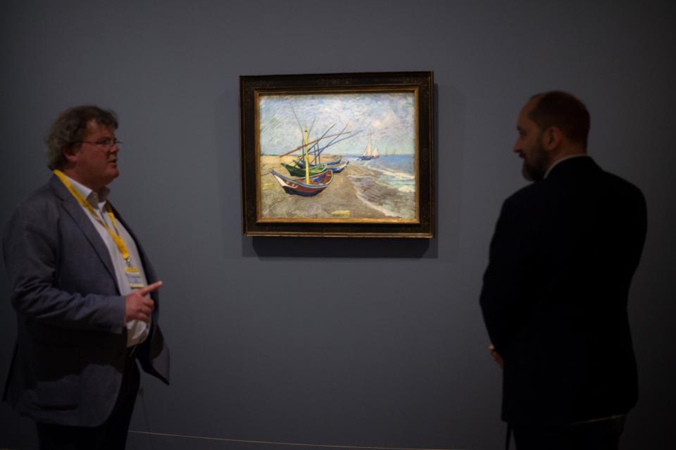 Men look at a painting by Vincent Van Gogh entitled 'Fishing Boats on the Beach at Les Saintes-Maries-de-la-Mer' during the exhibition 'Van Gogh in Provence: Modernizing Tradition' at the Fondation Vincent Van Gogh Arles on May 13, 2016 in Arles, southern France.&nbsp;