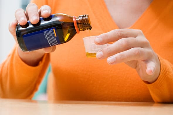 Woman pouring cough medicine