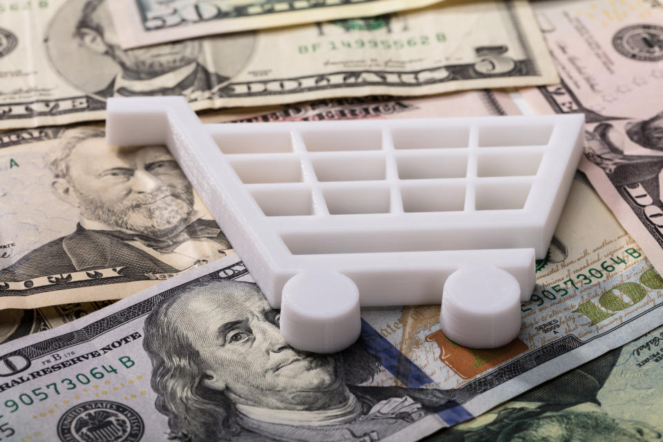 Shopping cart on top of a pile of money.