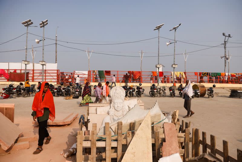 Devotees walk next to crates loaded with carved stones, which will be used for the decoration and revamp of the banks of the Sarayu river, in Ayodhya