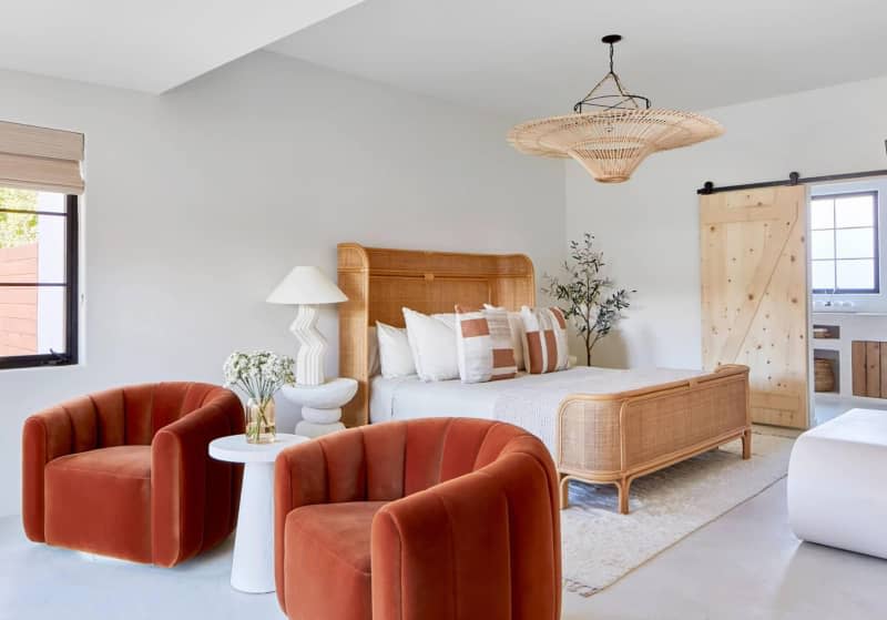 Cane bedframe in large bedroom with two copper colored suede arm chairs.