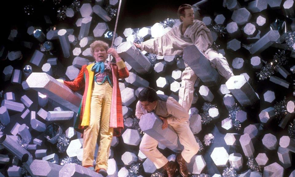 colin baker as the sixth doctor hanging from a series of glittery poles