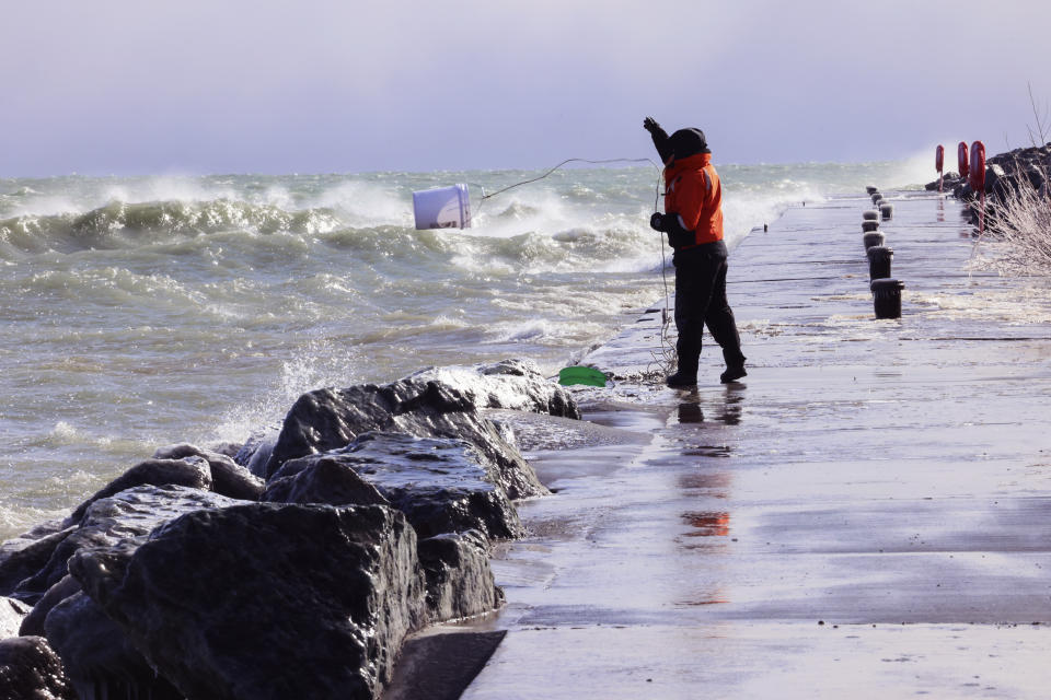 Rae-Ann Eifert, a lake monitor for the Wisconsin Department of Natural Resources, braved sub-freezing temperatures to gather buckets of water for testing off a Lake Michigan breakwater in Racine, Wis., on Feb. 28, 2024, as part of an effort across the Great Lakes to understand the effects of an iceless winter. Unseasonable warmth has left the Great Lakes all but devoid of ice, leaving scientists scrambling to understand the consequences as climate change accelerates. (AP Photo/Teresa Crawford)