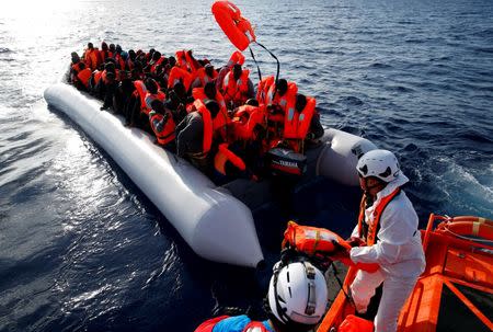 Migrants in a dinghy reach out for life jackets thrown to them by rescuers of the Migrant Offshore Aid Station (MOAS) some 20 nautical miles off the coast of Libya, June 23, 2016. REUTERS/Darrin Zammit Lupi