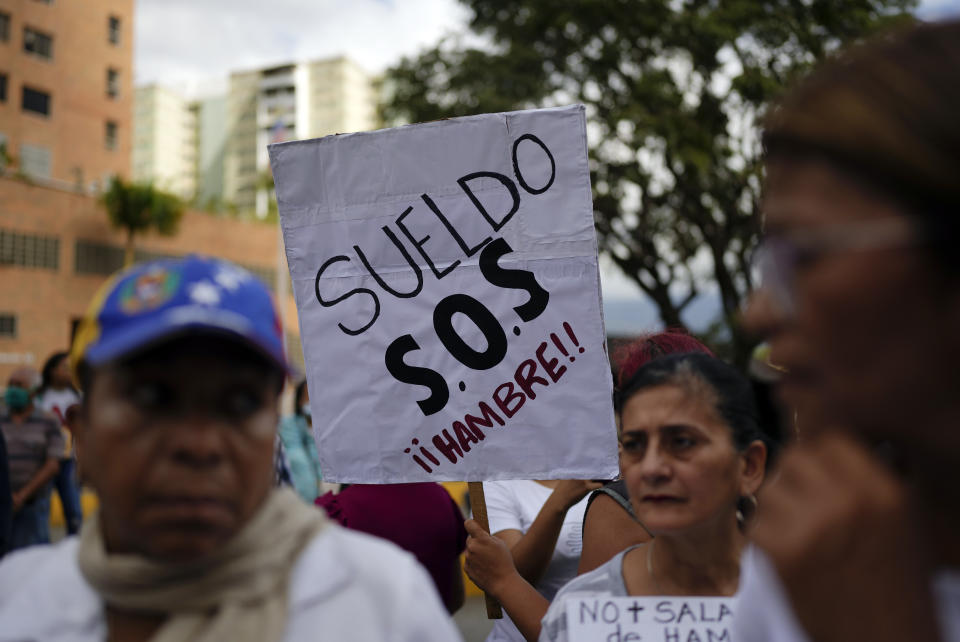 Teachers, other public workers and pensioners march for higher salaries and pensions, and payment of their full benefits, as one holds a sign that in Spanish reads "Salary. S.O.S. Hunger!" in Caracas, Venezuela, Thursday, Jan. 19, 2023. Protesters denounce that they are facing high food prices set in U.S. dollars amid low wages. The monthly minimum wage is about $7 dollars. (AP Photo/Ariana Cubillos)