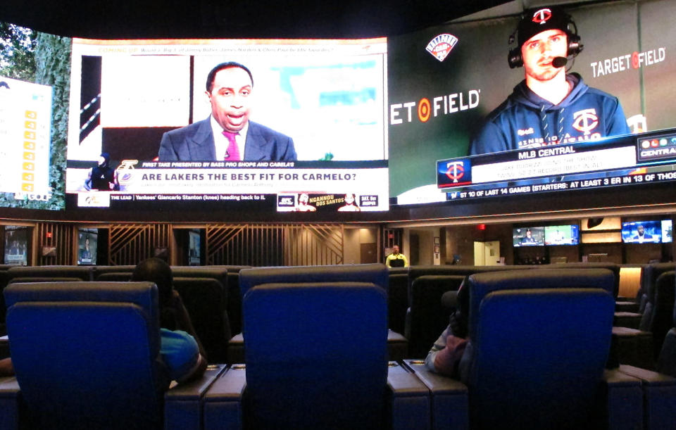 This Thursday, June 27, 2019 photo, shows customers watching giant video screens in the new sportsbook at Bally's casino in Atlantic City, N.J. Bally's and the Borgata casino are opening new sportsbooks worth more than $20 million. (AP Photo/Wayne Parry)