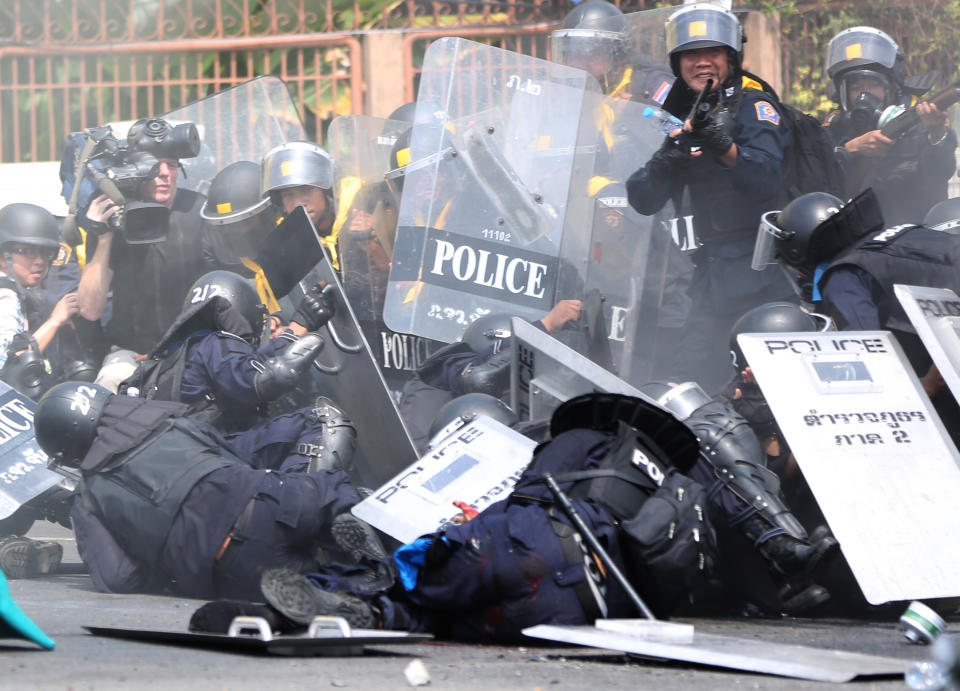 Riot police officers fall on the ground after a bomb blast near them during a clash with anti-government protesters Tuesday, Feb. 18, 2014 in Bangkok, Thailand. Clashes between police and anti-government demonstrators in Bangkok left two people dead and 57 others injured Tuesday as riot police attempted to clear out protest sites around the Thai capital. (AP Photo/Apichart Weerawong)