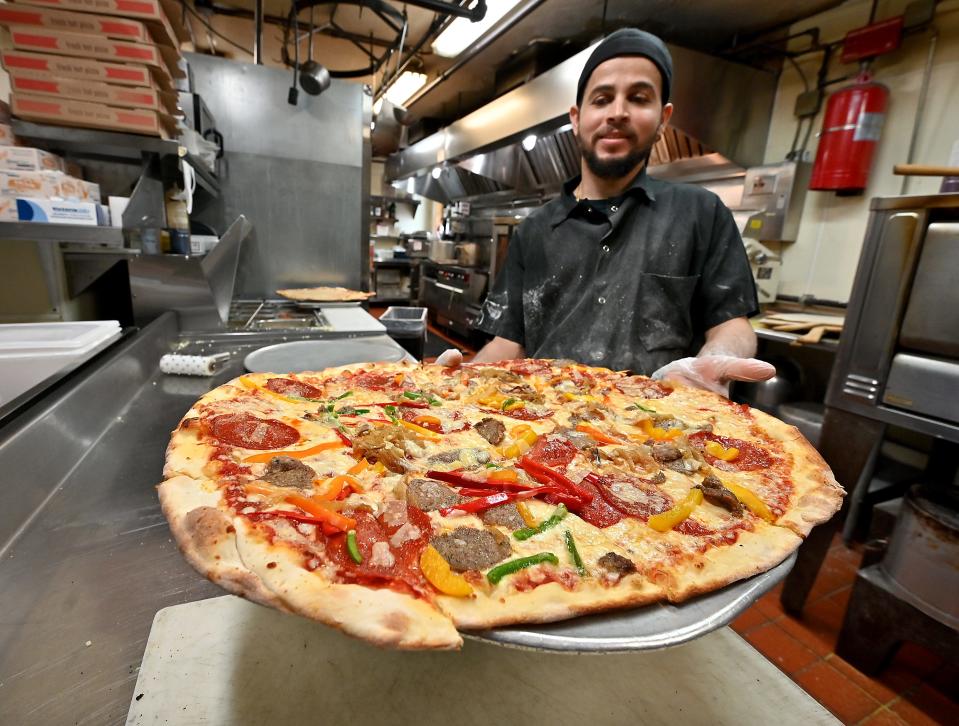 Peppercorns Grille & Tavern pizza chef Sebastian Gocalves holds a pepperoni, peppers, onions and meatball pizza.